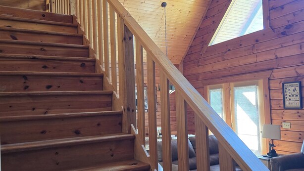A wooden staircase with a ceiling fan, leading to a living area with a couch and a window. - The Green Bear Cabin (Unit A) Near Jellystone/Three Bears Resort in Warrens, WI (Warrens)