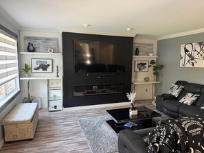 Un salon moderne avec un meuble de rangement noir pour appareils multimédias, un canapé, une table basse et des objets décoratifs.