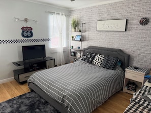 Ein Schlafzimmer mit einem Bett, einem Fernseher, einer Ablage mit Dekoration, einer Uhr und einem Schild an der Wand.