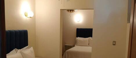 Hotellihuone, jossa on sänky, kattotuuletin ja yöpöytä.