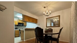 A dining area with a table and chairs, a chandelier, and a view into the kitchen.