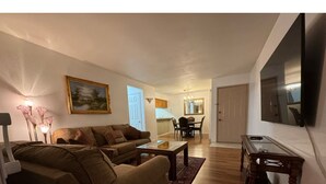 A living room with a sofa, a coffee table, and a TV mounted on the wall.