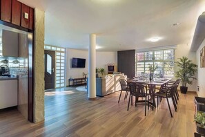 Amplia sala de estar con una mesa de comedor, sillas, un sofá y un televisor montado en la pared.