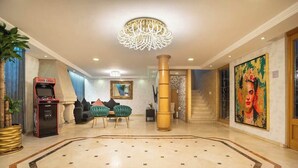 A lobby with a marble floor, a chandelier, a painting, a staircase, and a gaming machine. - Prime Polanco Stay With Patio, Near Shops & Cafes (Ciudad de México)