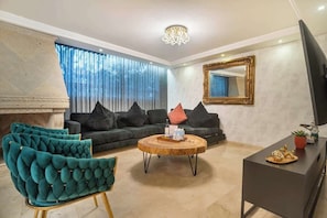 A living room with a sofa, a round coffee table, a TV stand, and a fireplace.