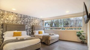 A hotel room with two beds, a large window, and a stone wall. - Prime Polanco Stay With Patio, Near Shops & Cafes (Ciudad de México)