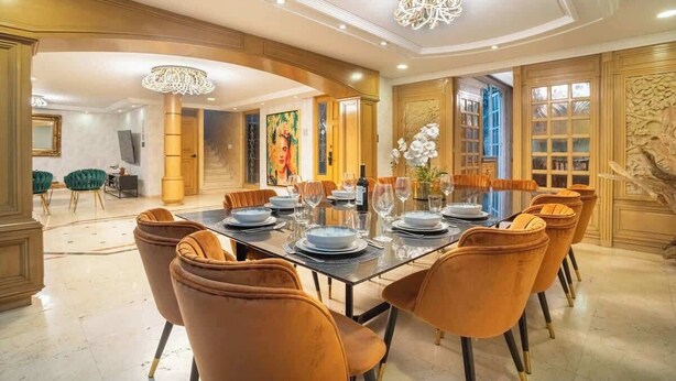 A dining area with a long table set for six, surrounded by velvet chairs, with a chandelier above. - Prime Polanco Stay With Patio, Near Shops & Cafes (Ciudad de México)