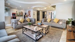 A modern living room with two grey sofas, a coffee table, and a gaming console.