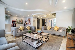 A modern living room with two grey sofas, a coffee table, and a gaming console. - Luxe Polanco Home Private Yard and Private Patio (Mexico City)