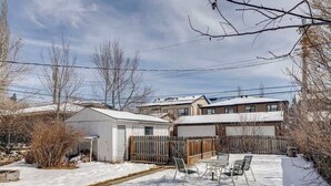 Um bairro residencial com garagem, quintal cercado e chão coberto de neve.
