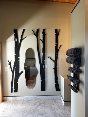 Un intérieur moderne agrémenté d’une sculpture d’arbre fixée au mur, d’un miroir et d’un porte-serviettes.