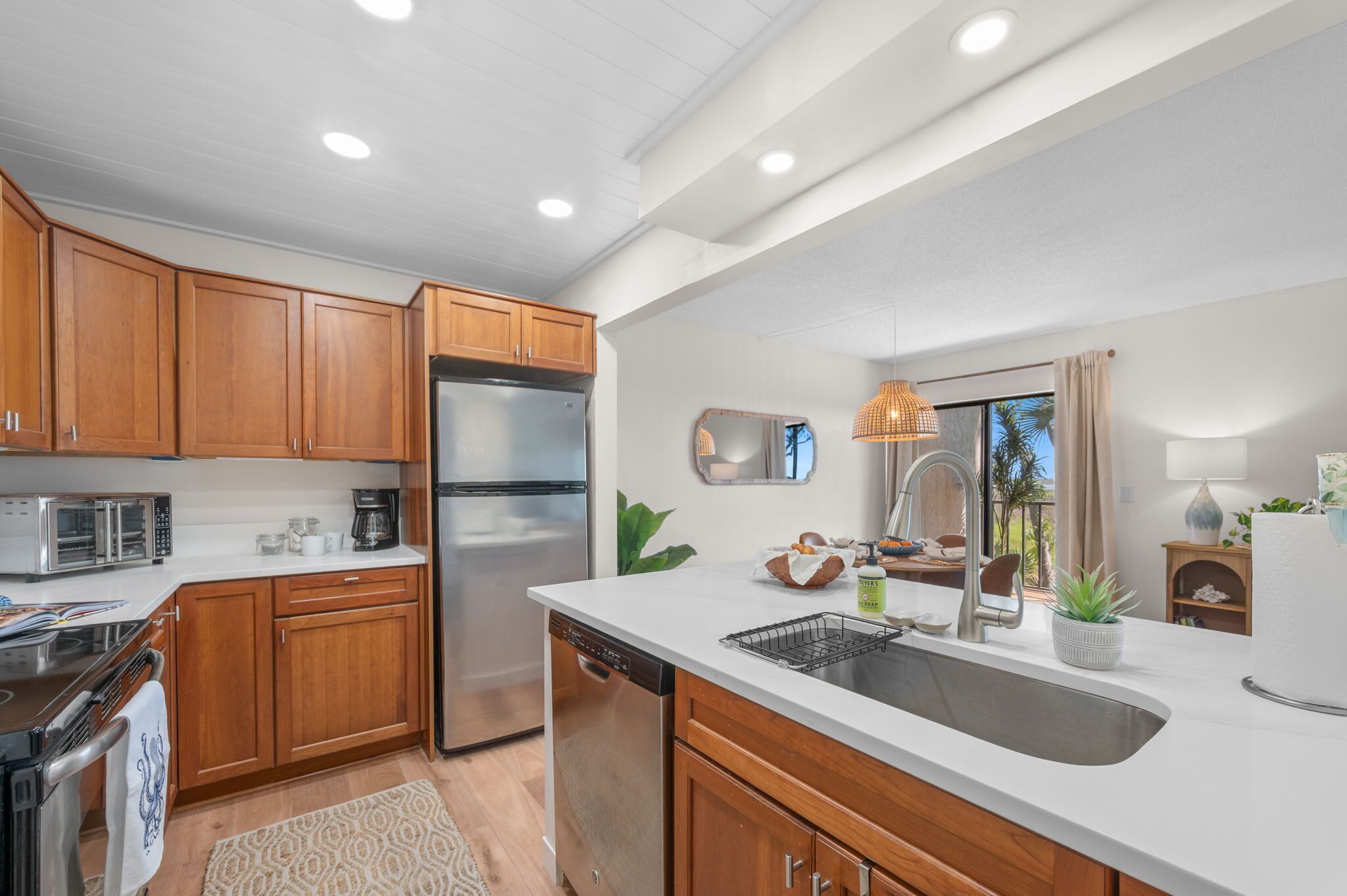 A modern kitchen with wooden cabinets, stainless steel appliances, a dishwasher, and a large sink.