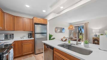 A modern kitchen with wooden cabinets, stainless steel appliances, a dishwasher, and a large sink.