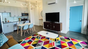 Una sala de estar moderna con un sofá, una mesa de comedor, un televisor y una alfombra colorida.