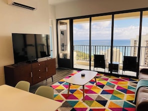 A balcony with a view of the sea, a flat-screen TV, a dining area, and a colorful rug. - Penthouse Suite, Top Floor Panoramic Ocean View with AC & Free Parking (Honolulu)