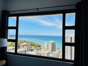 A room with a large window offering a view of the ocean and cityscape. - Penthouse Suite, Top Floor Panoramic Ocean View with AC & Free Parking (Honolulu)