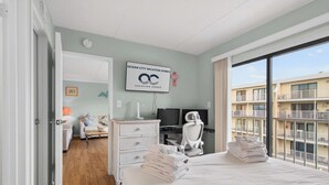 Quarto de hotel com cama, escrivaninha, cadeira, televisão e vista para o edifício.