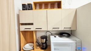 A compact kitchenette with a microwave, coffee maker, and storage cabinets. - Edifício VIvaVida (Sinop)