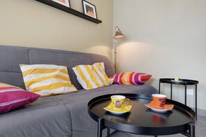 A modern living room with a grey sofa, striped cushions, a black coffee table, and a floor lamp. - Location 300 m from the Beach (Roscoff)