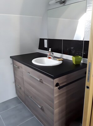 Ein Badezimmer mit einem weißen Waschbecken, einer schwarzen Arbeitsplatte und Holzschränken.