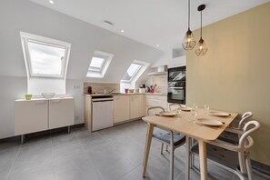 Eine moderne Küche mit Dachfenstern, einem Essbereich mit Tisch für vier Personen und einem eingebauten Backofen.