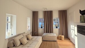 Ein geräumiges Wohnzimmer mit einer großen Couch, einer kleineren Couch, einem Teppich und einem Kamin.