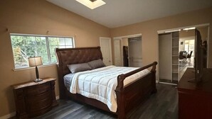 Un dormitorio con cama, cómoda, mesita de noche, ventana y tragaluz.