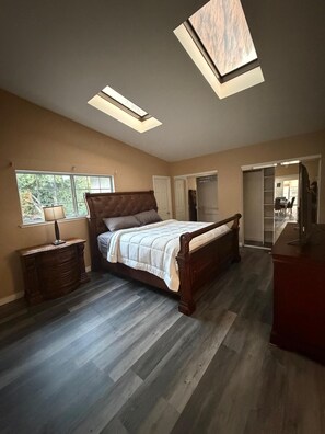 Ein Schlafzimmer mit Bett, Kommode, Nachttisch, Fenster und Dachfenster.