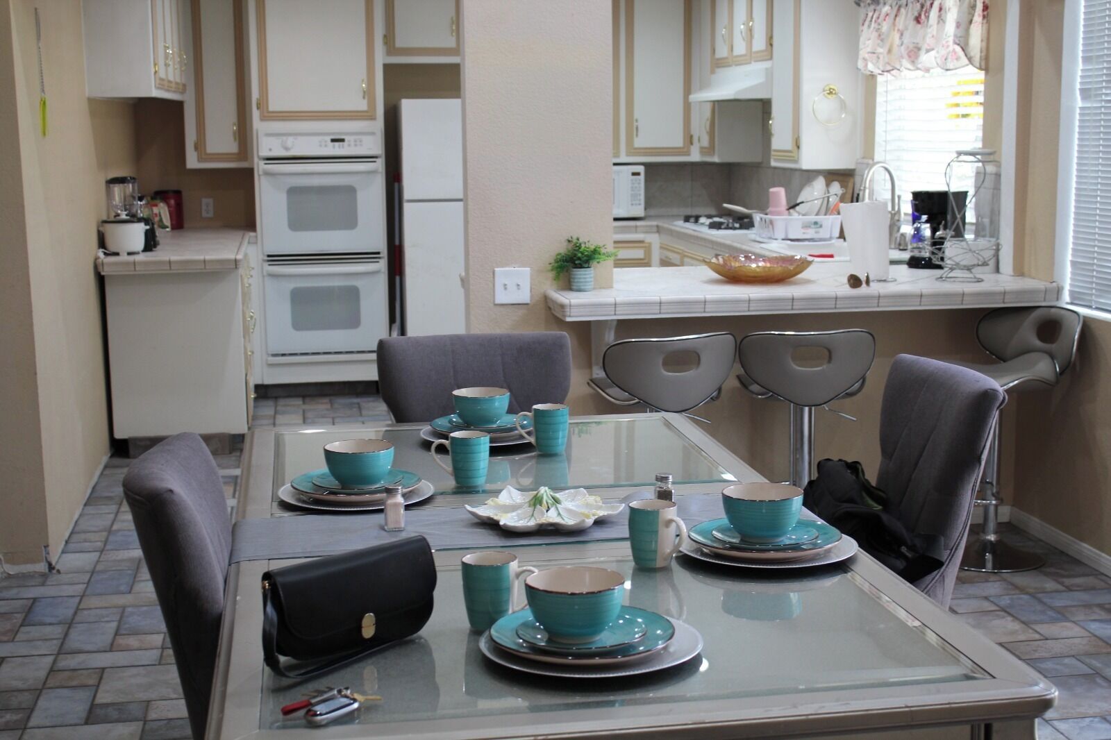 A dining area with a glass table set for four, surrounded by chairs.
