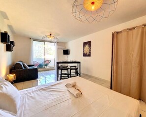 A hotel room with a bed, a desk, a chair, a TV, and a window.
