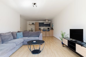 A modern living room with a grey sofa, a round coffee table, and a TV on a black stand. - Bright 3BDR Canalside Flat in Hackney (London)