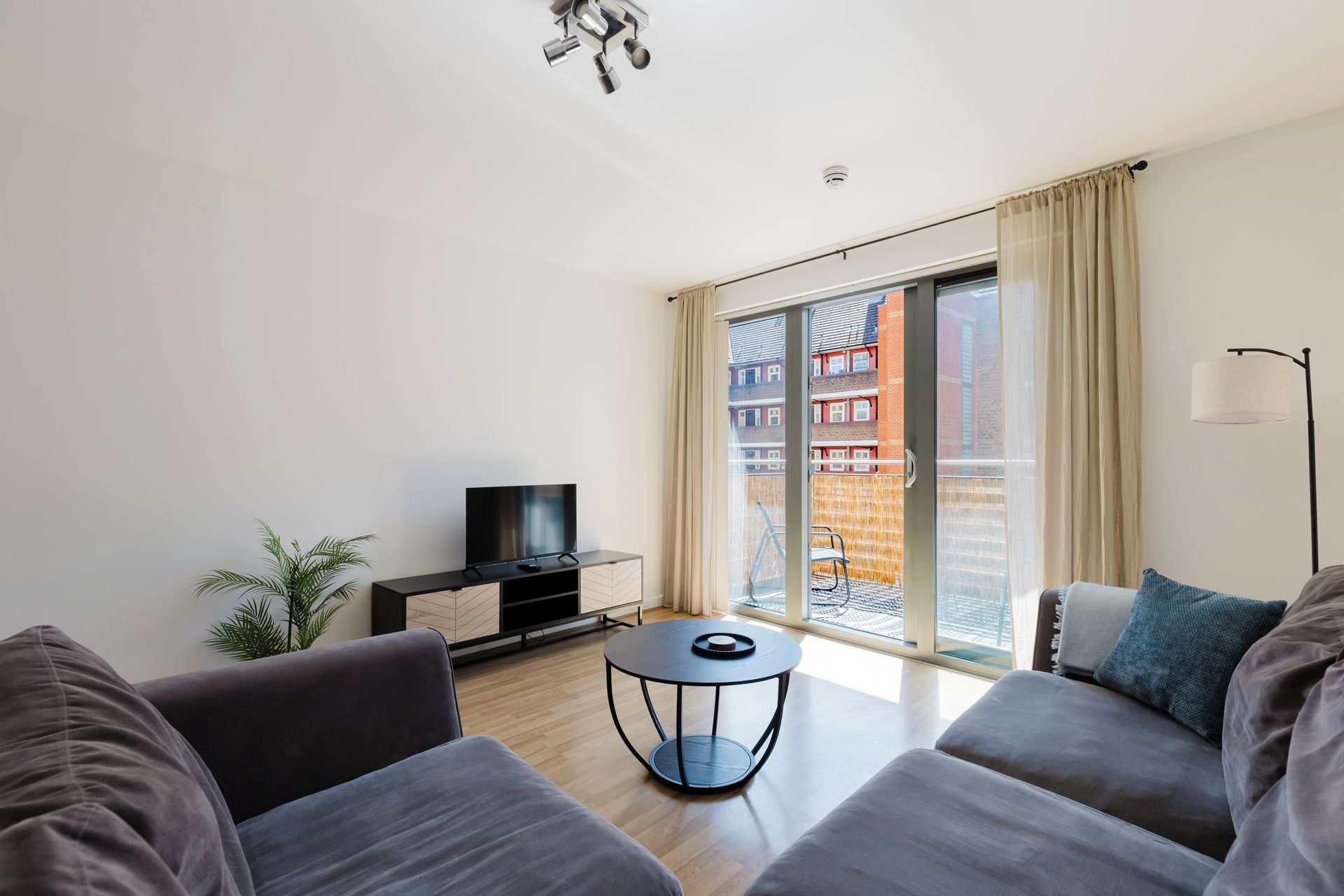 A modern living room with a flat-screen TV, a round coffee table, and a sofa.