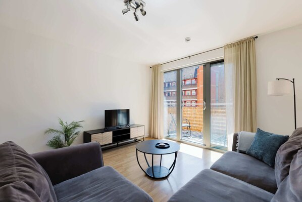 Ein modernes Wohnzimmer mit Flachbildfernseher, rundem Couchtisch und Sofa.