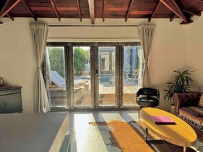 A room with a sliding glass door leading to an outdoor area, a sofa, a chair, and a small table with a notebook. - Welcoming 1-bedroom house with AC / pool / table tennis in vibrant Los Angeles (Los Angeles)