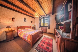 A bedroom with a wooden bed, a nightstand, a dresser, a window with curtains, and a bookshelf. - Gite du Puy la Besse - sleeps 11 - Corrèze Ussel (Ussel)