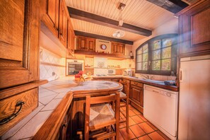 Une cuisine avec des meubles de rangement en bois, une table à manger avec des chaises, un four à micro-ondes et un lave-vaisselle.
