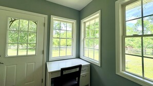 Ein Zimmer mit Schreibtisch und zwei Fenstern.