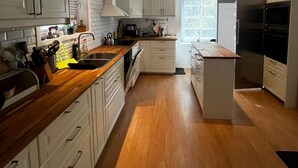 Una cocina moderna con armarios blancos, encimeras de madera y una isla central.