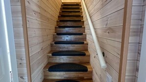 Una escalera de madera con barandilla y peldaños alfombrados de color negro.