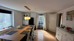 Un comedor con una mesa y sillas de madera, un armario blanco y una ventana con persianas.