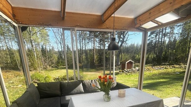 Un espacio de estar al aire libre con techo, una mesa, cojines y vistas del paisaje circundante.
