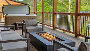 Eine Terrasse mit Gartenmöbeln, einem Feuerkorb und einem Whirlpool.