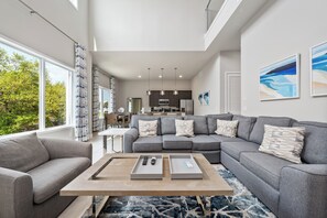 A modern living room with a sectional sofa, a coffee table, and artwork on the walls. - Beautiful Condo with Private Terrace Near Attractions (Kissimmee)