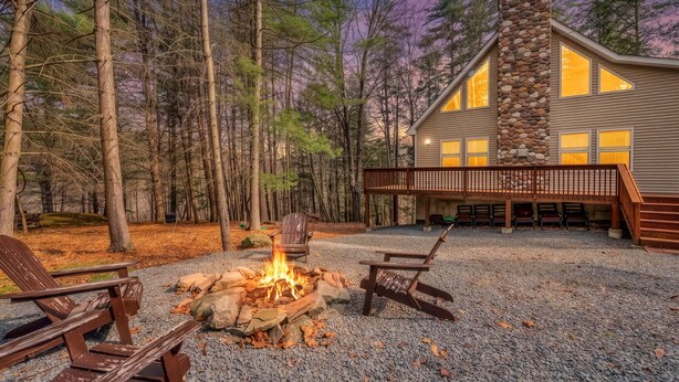 A cabin with a stone fireplace, outdoor seating, and a deck overlooking a forest. - Stonewood Retreat AC, Firepit, Pool Tble, Masthope (Lackawaxen)