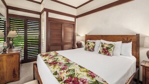 A hotel room with a large bed, wooden headboard, and a view through a sliding door. - Kiahuna Plantation Resort 58 Royal Garden 1 BD (Koloa)