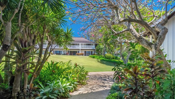 A pathway leading to a house surrounded by lush greenery and a clear blue sky. - Kiahuna Plantation Resort 58 Royal Garden 1 BD (Koloa)