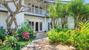 A building with a balcony, surrounded by lush greenery and a concrete pathway. - Kiahuna Plantation Resort 58 Royal Garden 1 BD (Koloa)