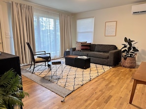 A living room with a sofa, a chair, a coffee table, a rug, and a plant.