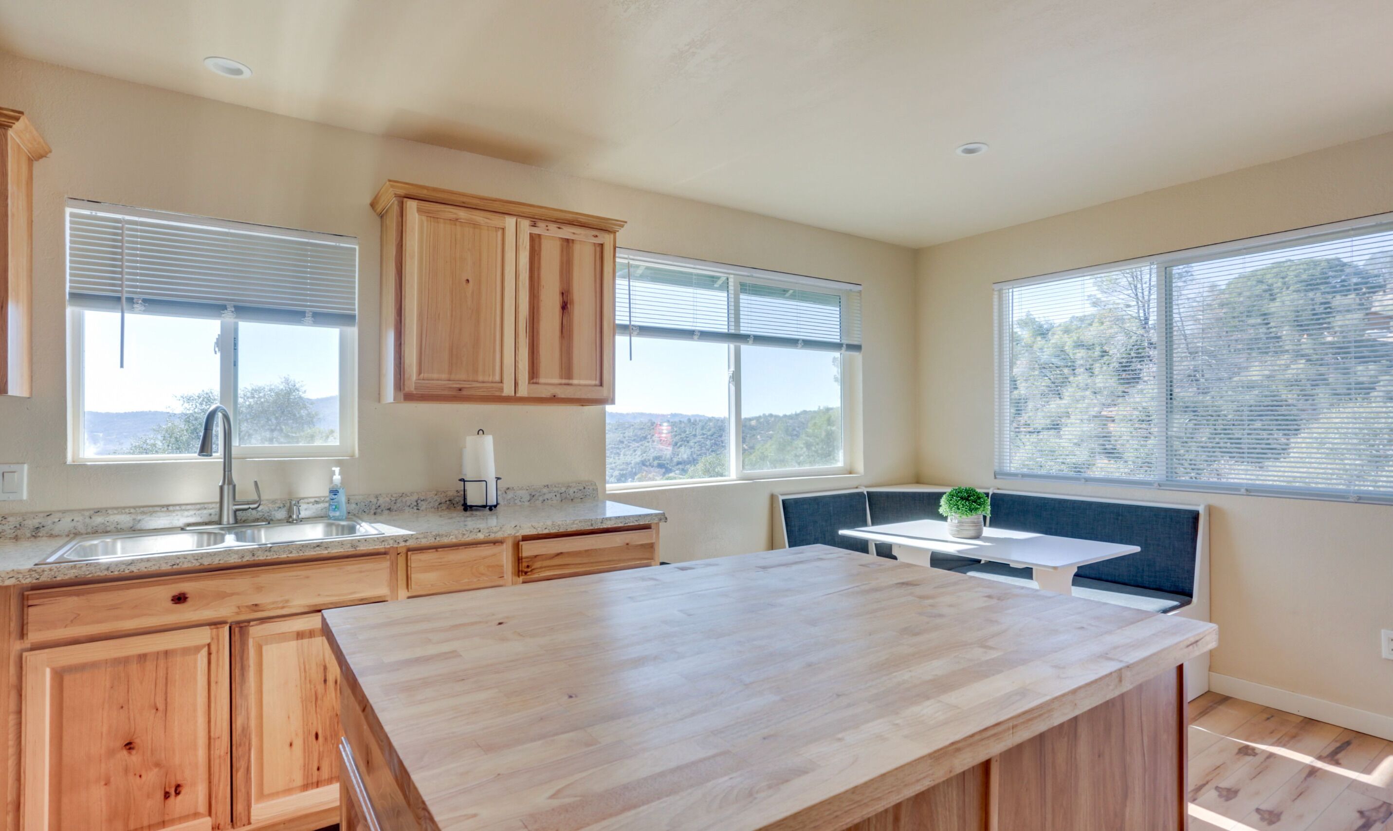 A kitchen with wooden cabinets, a granite countertop, a sink, and a window with a view.
