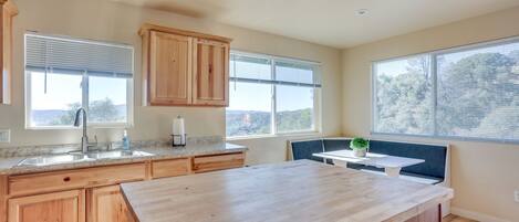 A kitchen with wooden cabinets, a granite countertop, a sink, and a window with a view.